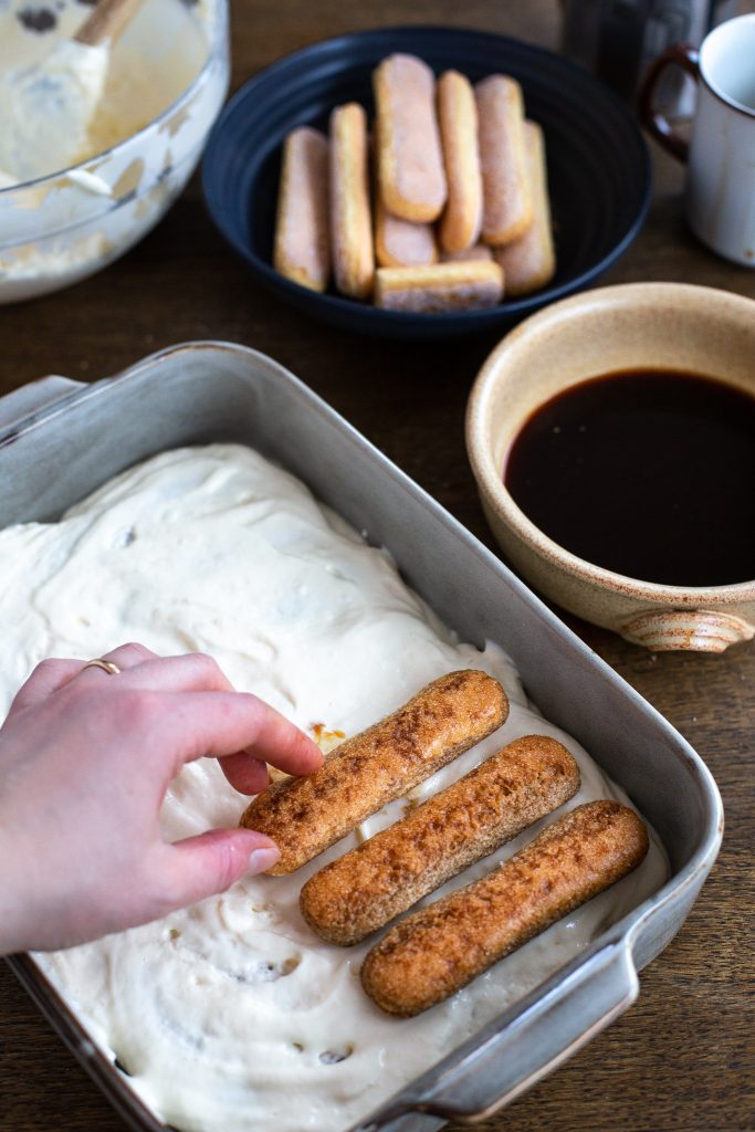 Arranging a layer of savoiardi over mascarpone cream.