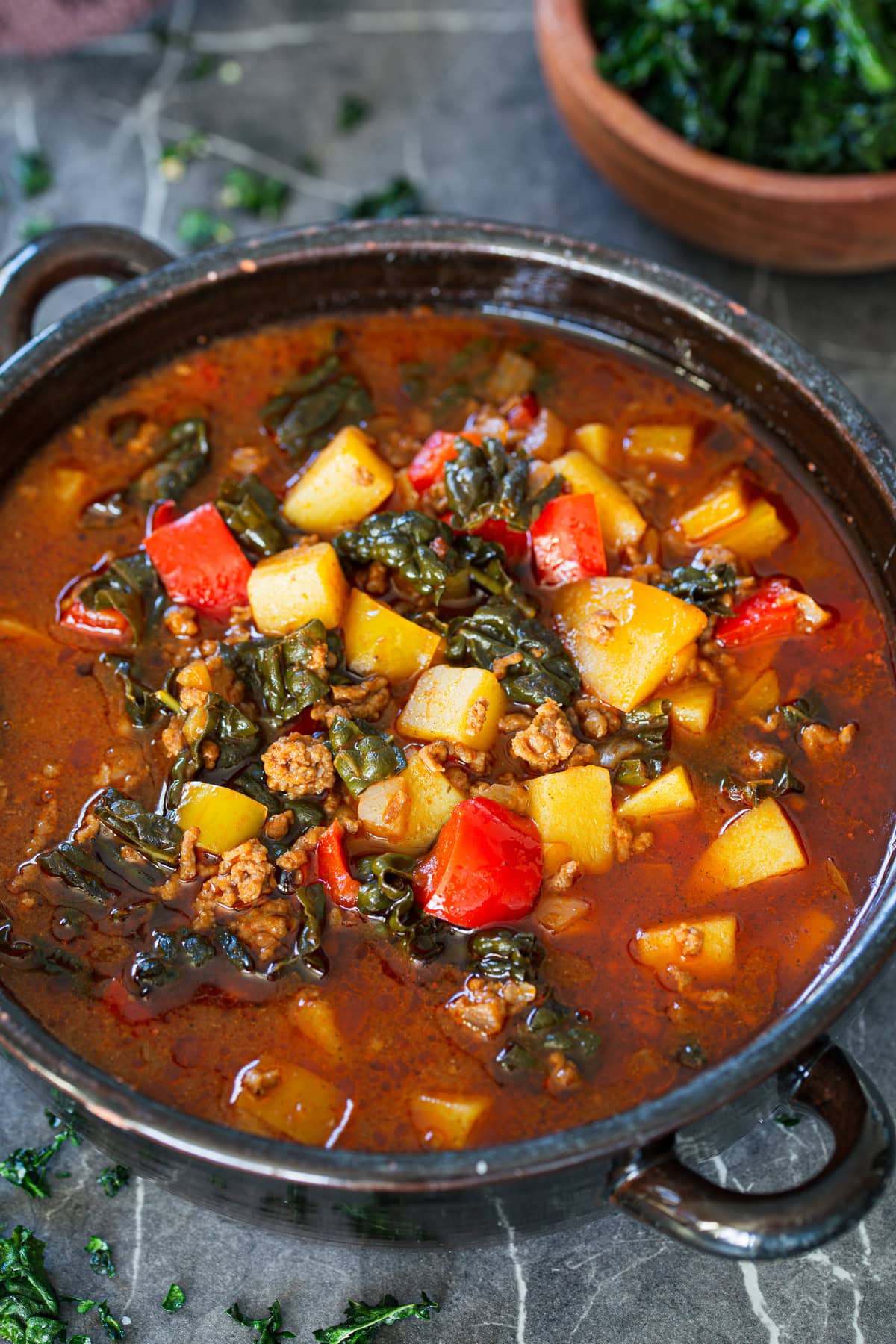Bowl of hearty meat soup with cavolo nero, diced peppers and potatoes