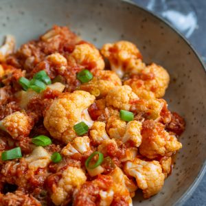 A portion of tomato pickled cauliflower on a serving plate.