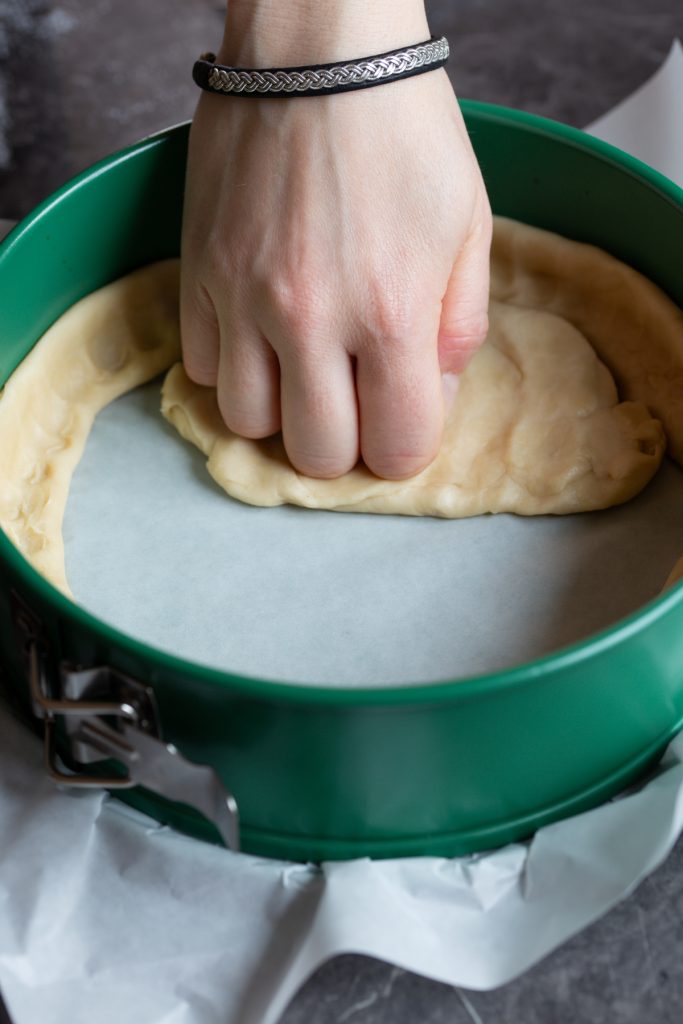 Hands pressing pie dough into pan.