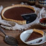 A slice of chocolate tart in the front, rest of pie in the back.
