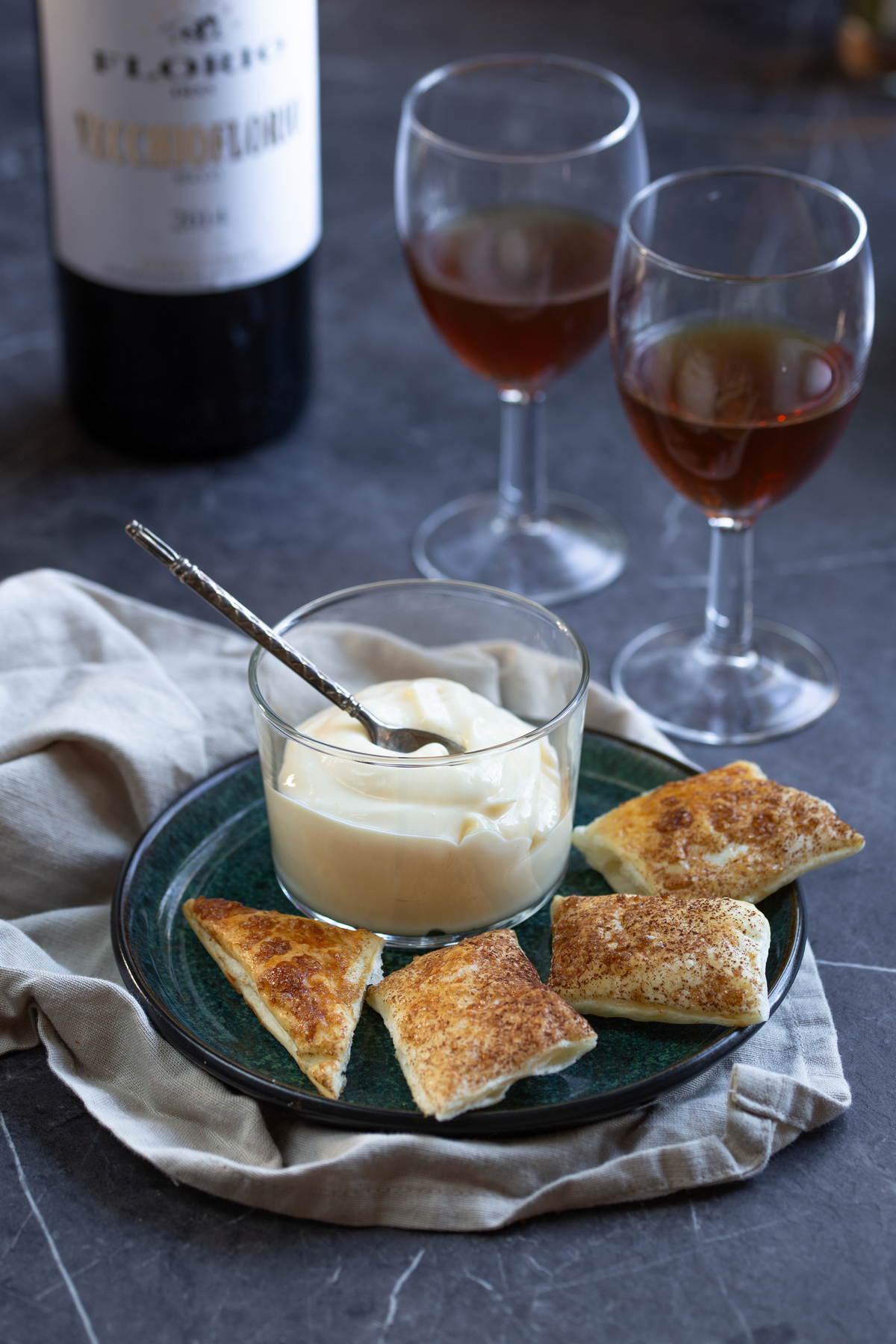 A cup of mascarpone cream with puff pastry served with marsala wine in glasses.