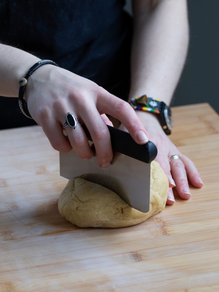 Cutting pasta dough with a bench scraper.