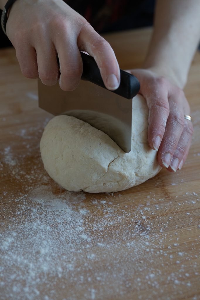 Portioning a ball of gnocchi dough with a bench scraper.