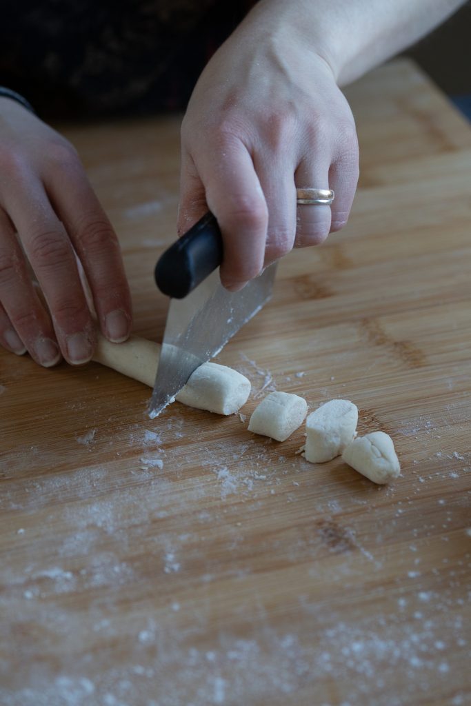 Cutting out gnocchi from dough sausage.