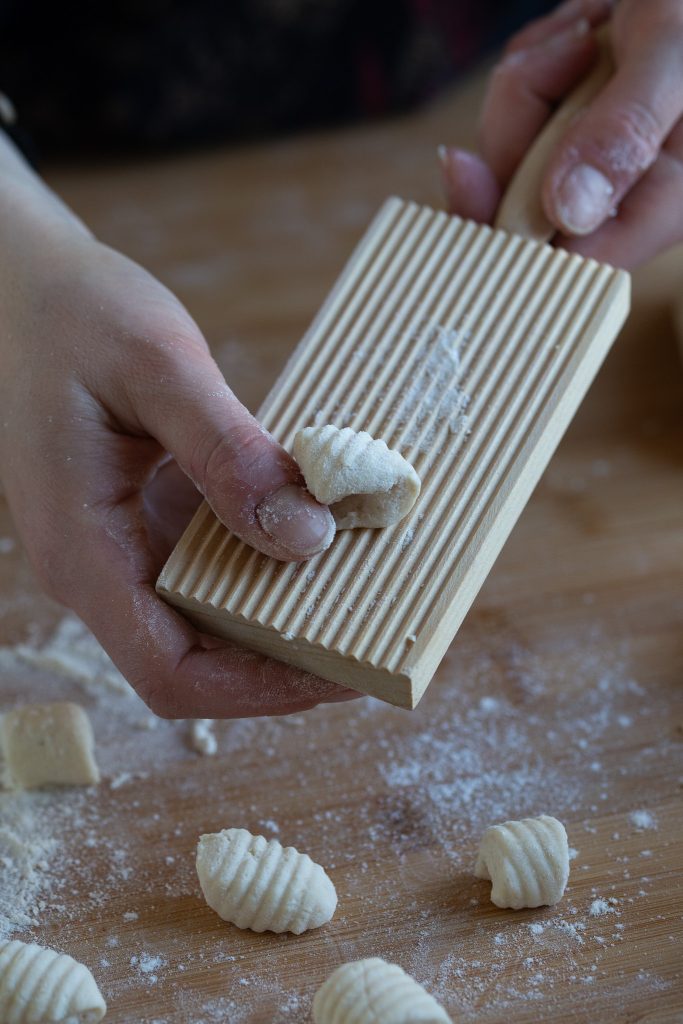 Shaping ricotta gnocchi on a gnocchi board.