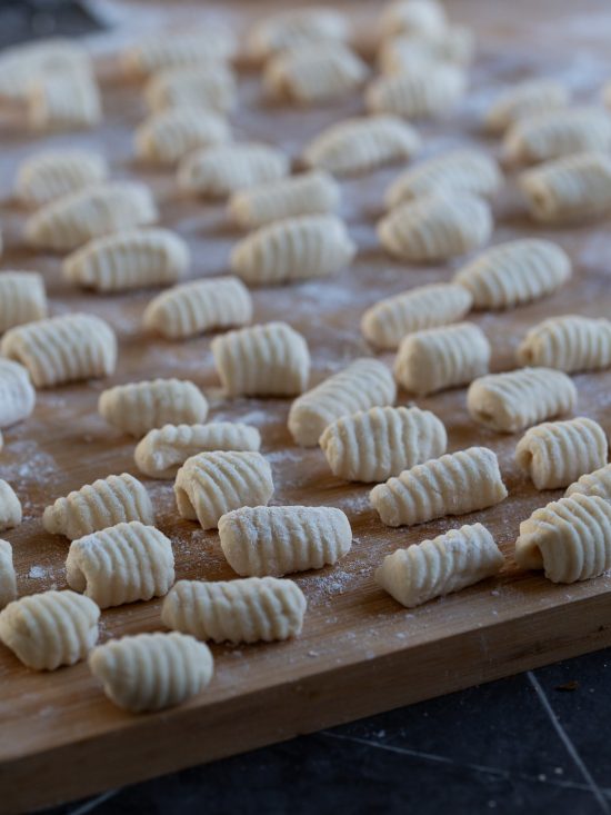 Uncooked ricotta gnocchi on a floured surface.