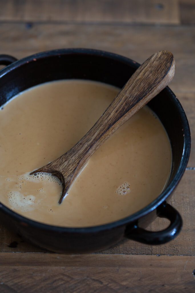 Cream mixture in a black ceramic pot.