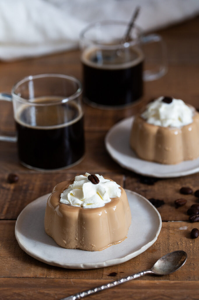 Instant coffee panna cotta served with whipped cream and a coffee bean on top.