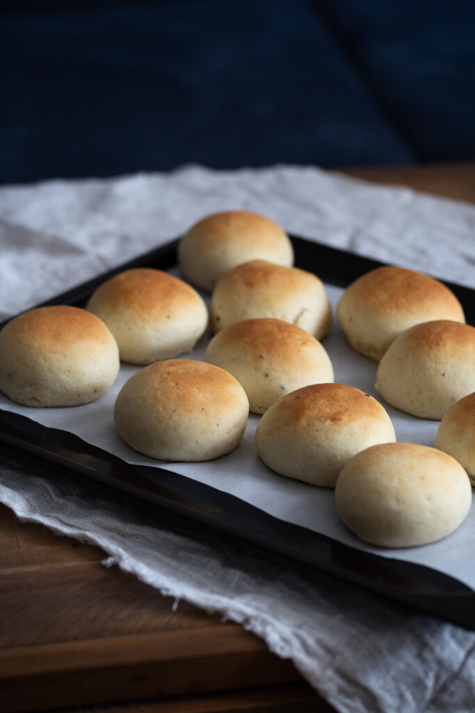 Baked cardamom buns on an oven tray.