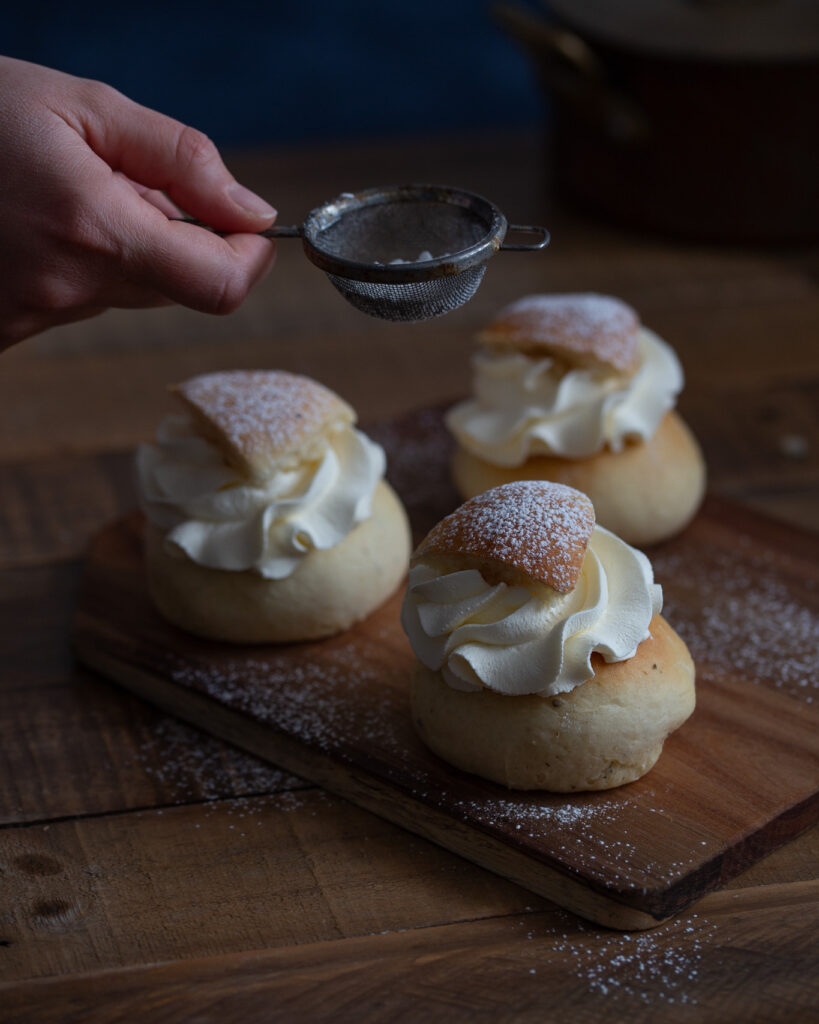 Dusting powdered sugar on cream buns.