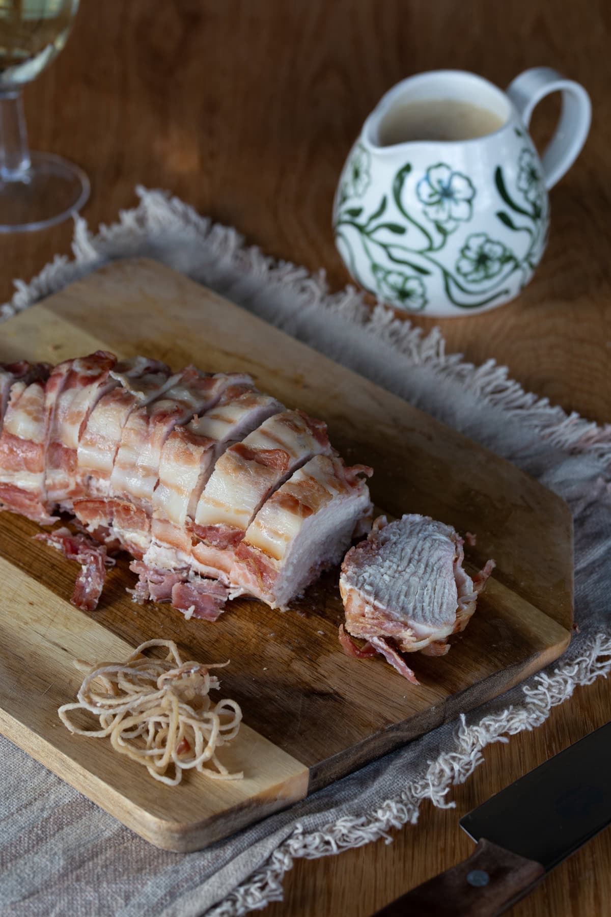 Bacon wrapped turkey breast roast sliced on cutting board.