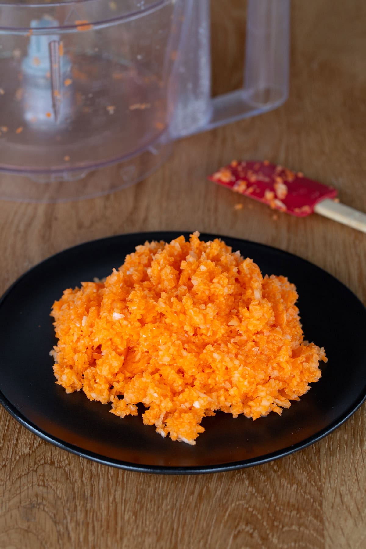 Minced carrot and onion on a black plate.