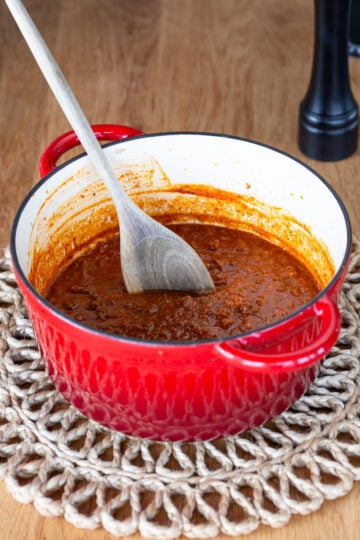 Red Dutch oven containing game meat ragu.