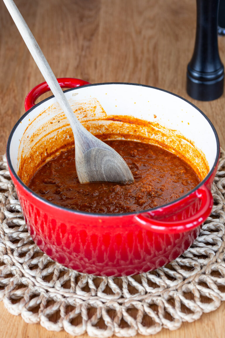 Red Dutch oven containing game meat ragu.