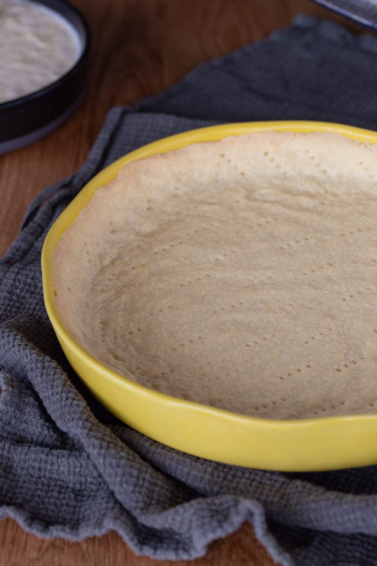 A partially baked shortcrust pastry in a yellow dish.