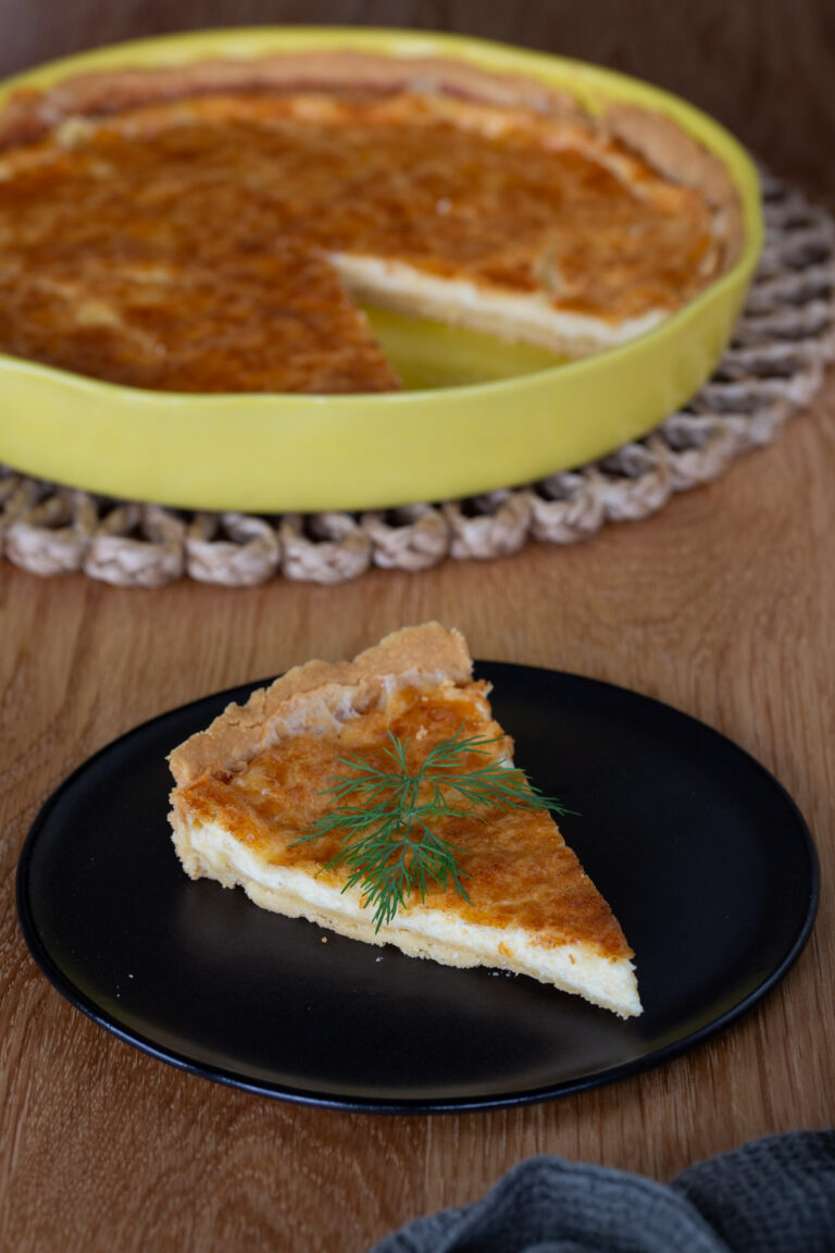 A slice of Västerbottenpaj, rest of pie in the background.