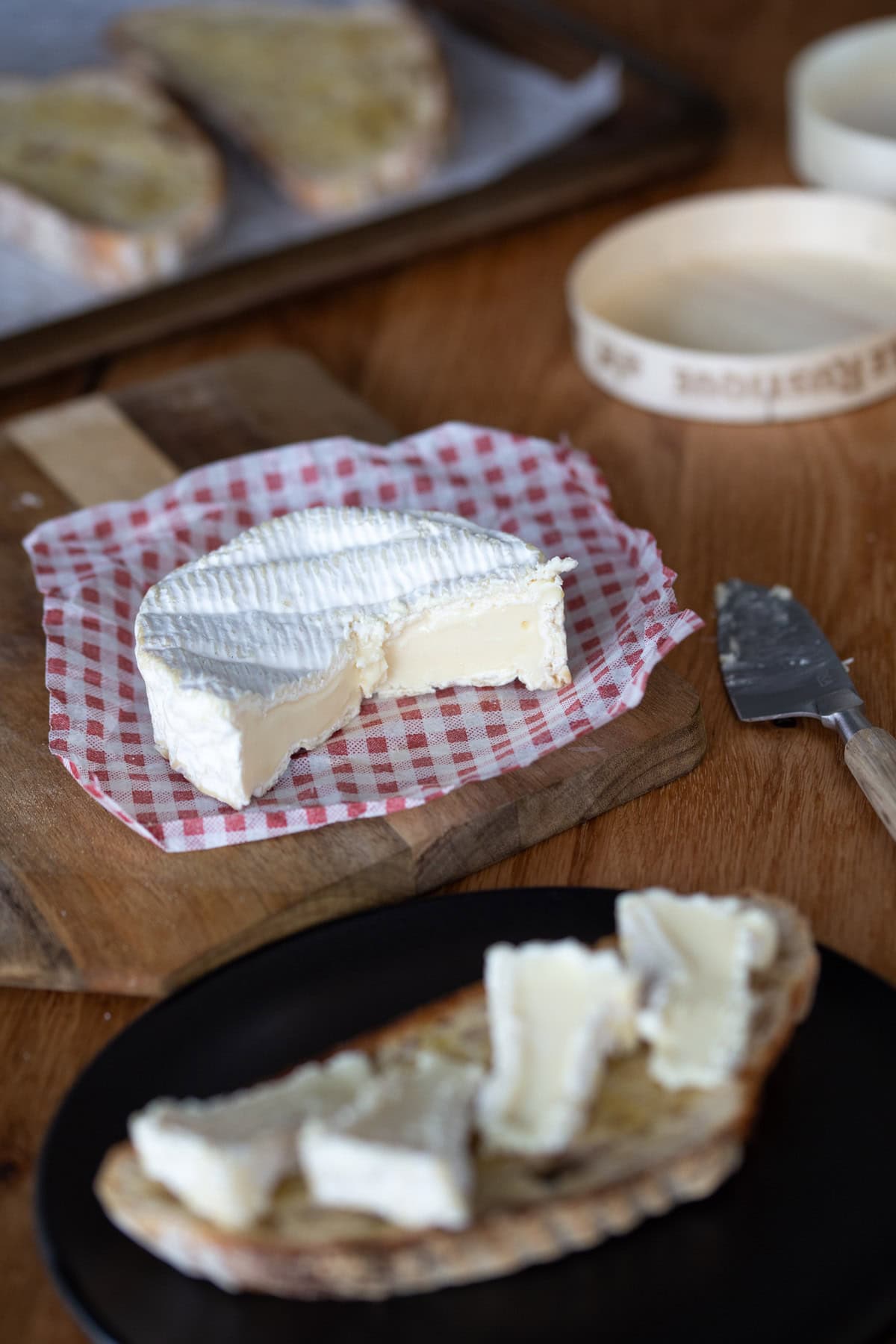 Camembert cheese form cut, slices on bread.