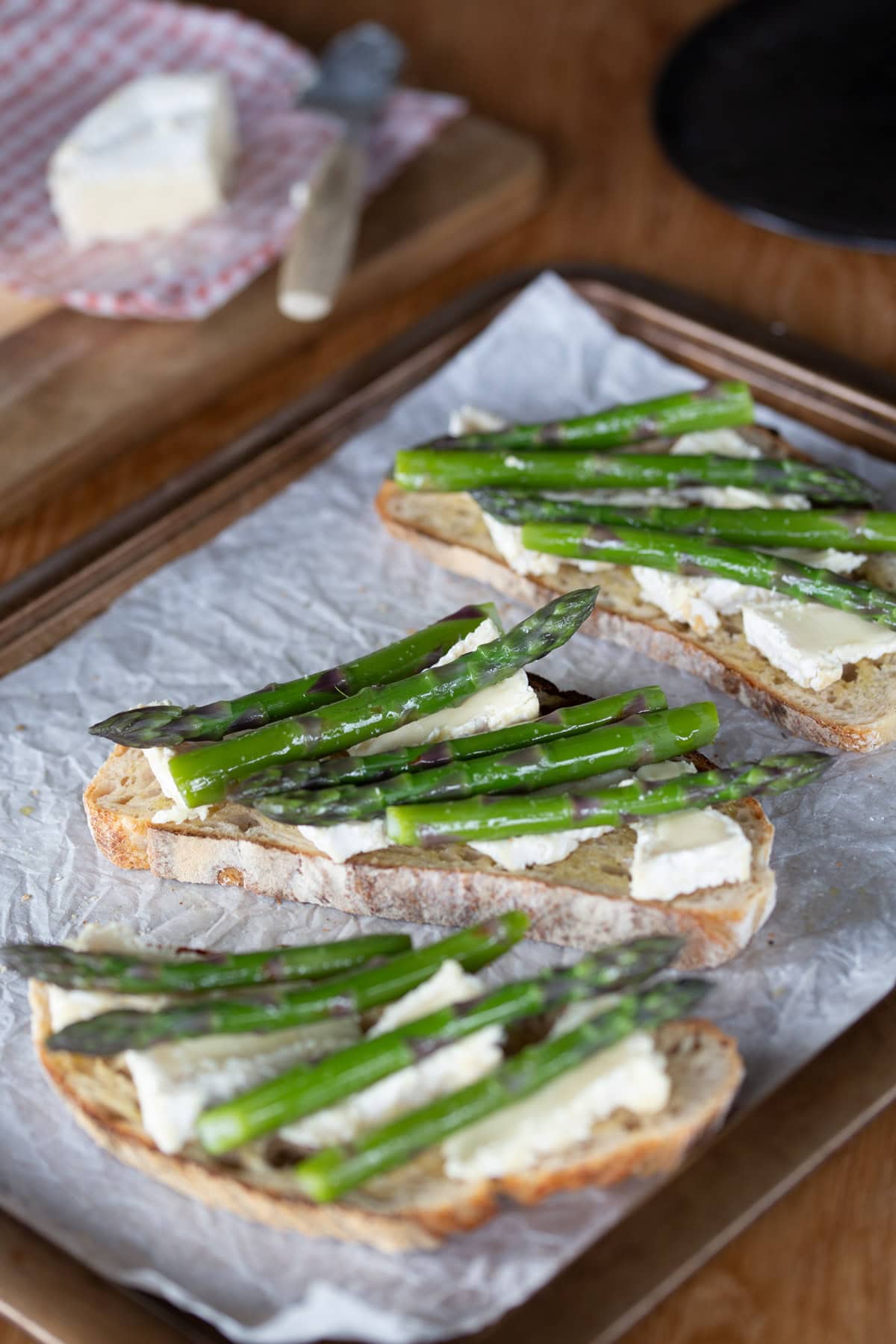 Asparagus and camembert bruschetta on oven tray.