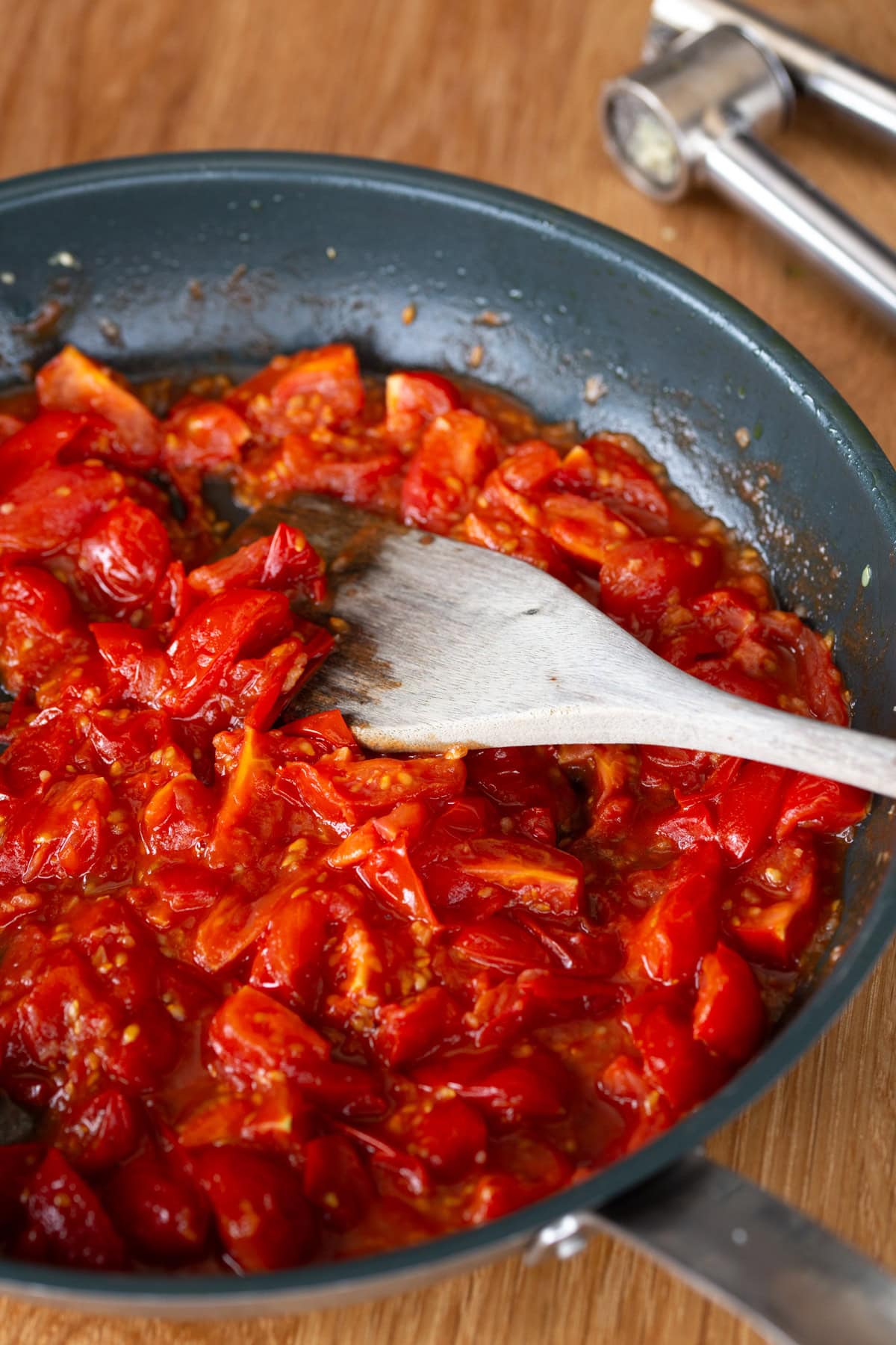 Cherry tomatoes being sauteed in a pan.