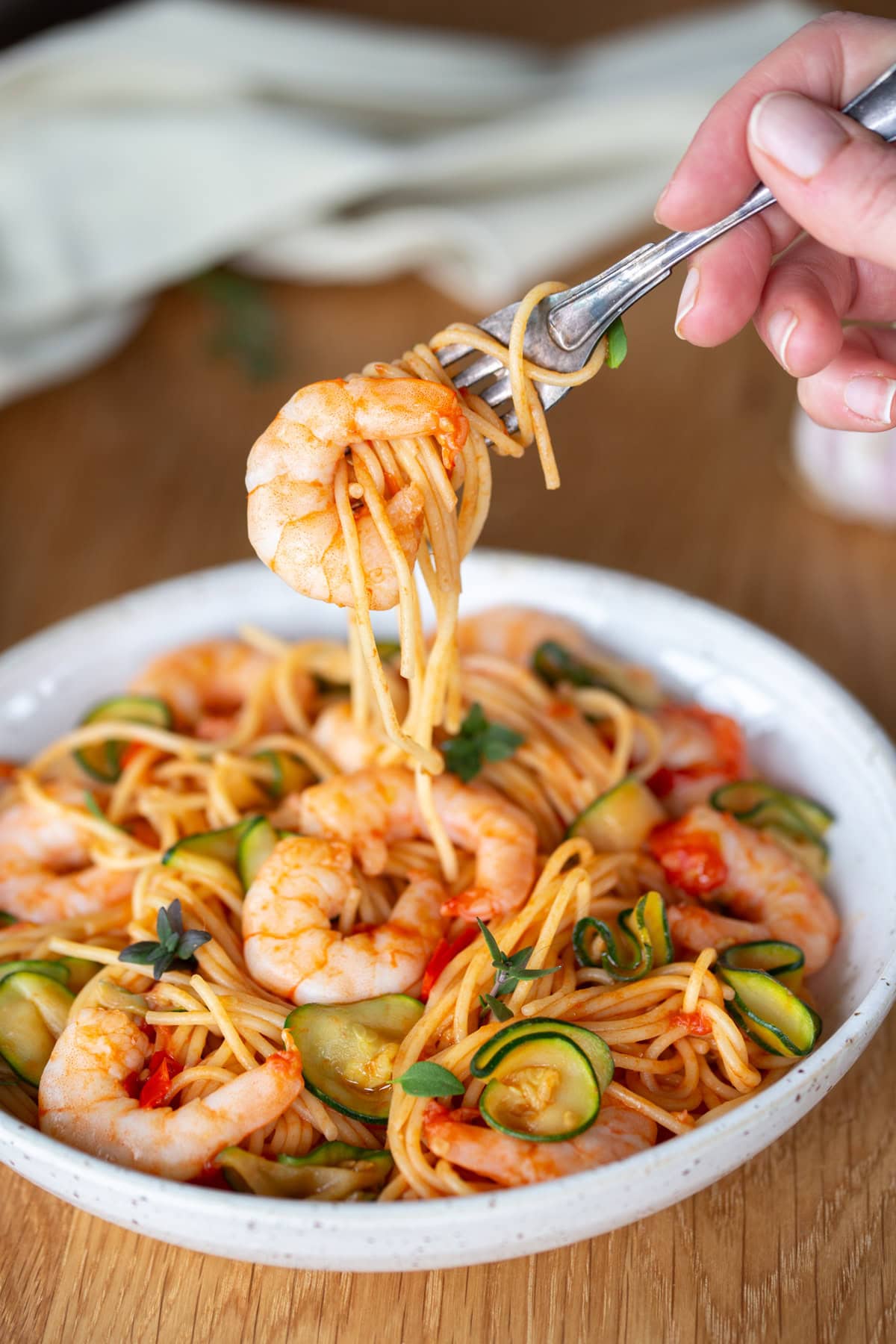 Fork lifting forkful of cherry tomato pasta with shrimp and zucchini..ì