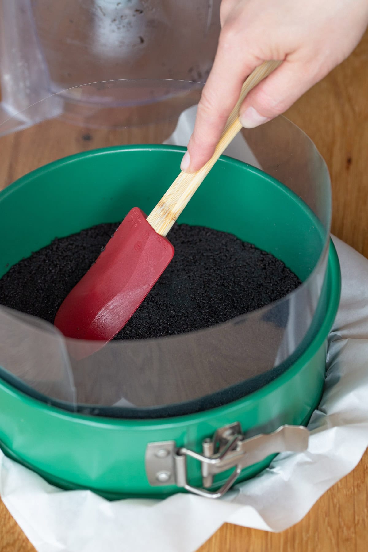 Spreading cookie base over the bottom of a springform pan with a silicone spatula.