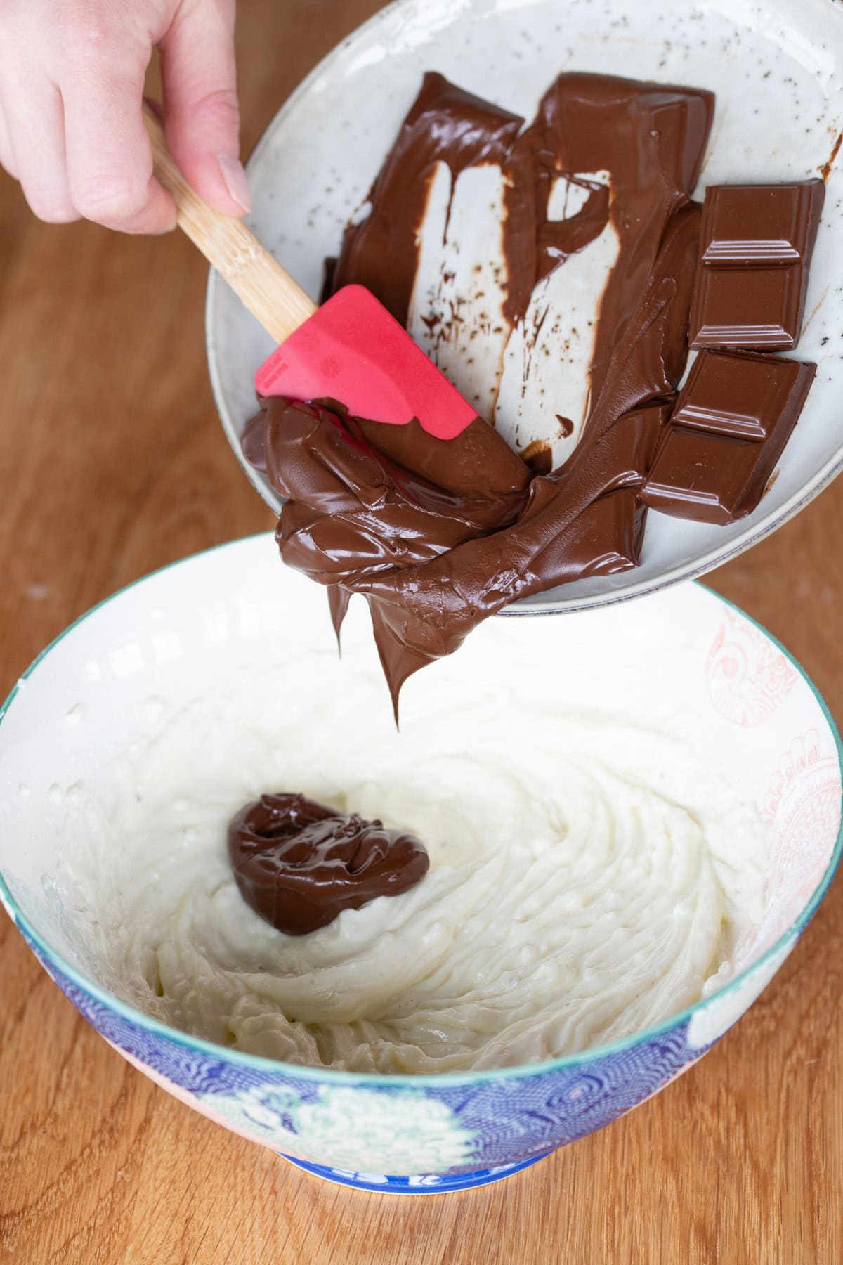 Pouring melted chocolate onto cheesecake mix.