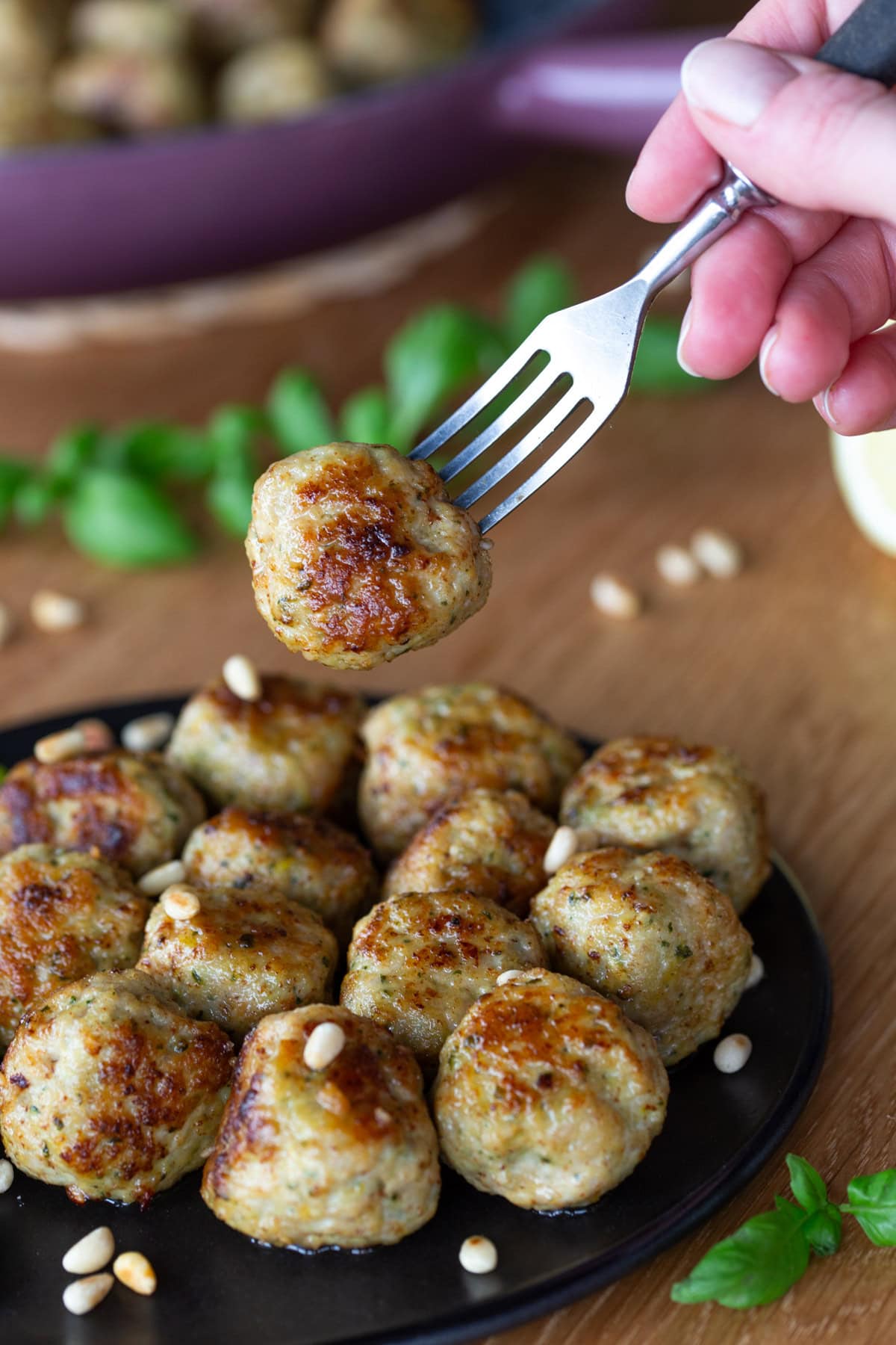 Hand holding fork with one chicken meatball over the rest of the portion.