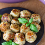 Lemon basil chicken meatballs on a black plate.