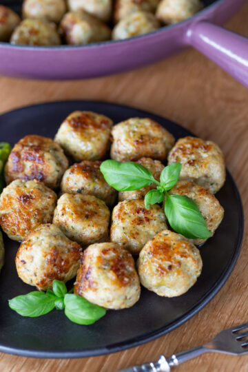 Lemon basil chicken meatballs on a black plate.
