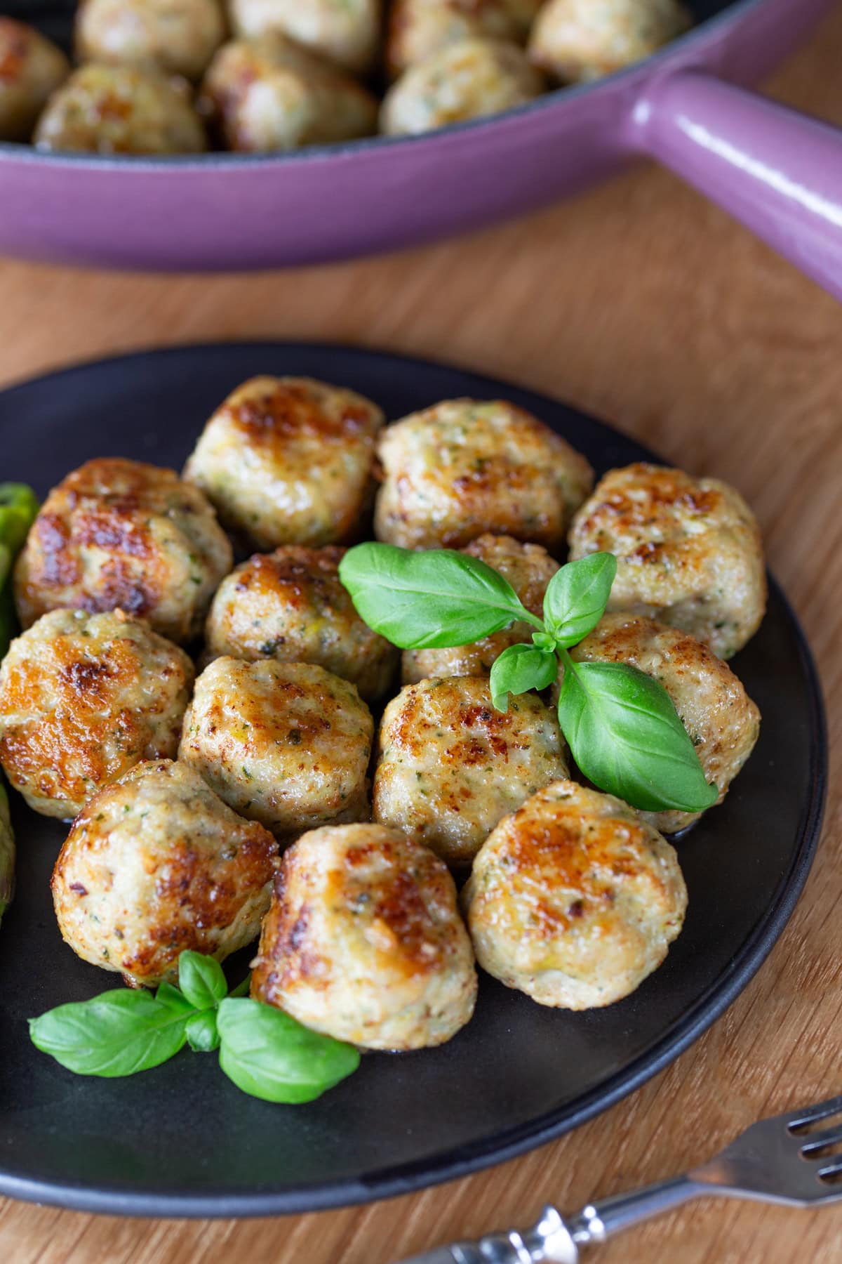 Lemon basil chicken meatballs on a black plate.