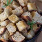 Sourdough bread croutons in a black bowl.