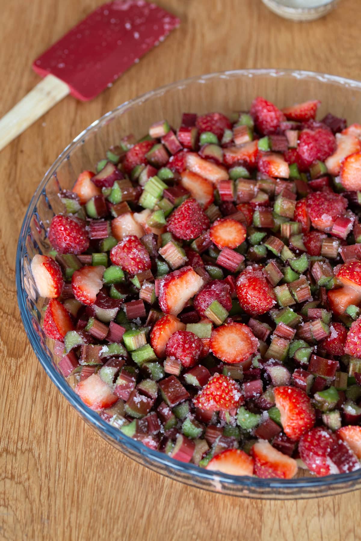 Chopped strawberries and rhubarb with sugar on the bottom of a pyrex form.