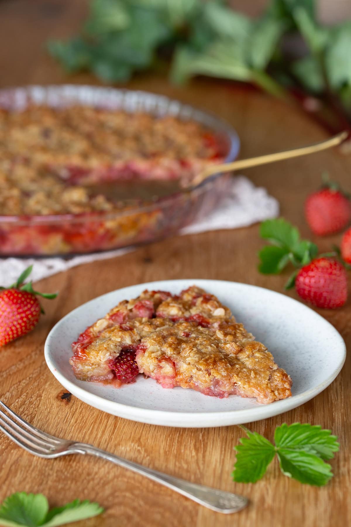One slice of strawberry rhubarb crisp on a white plate.