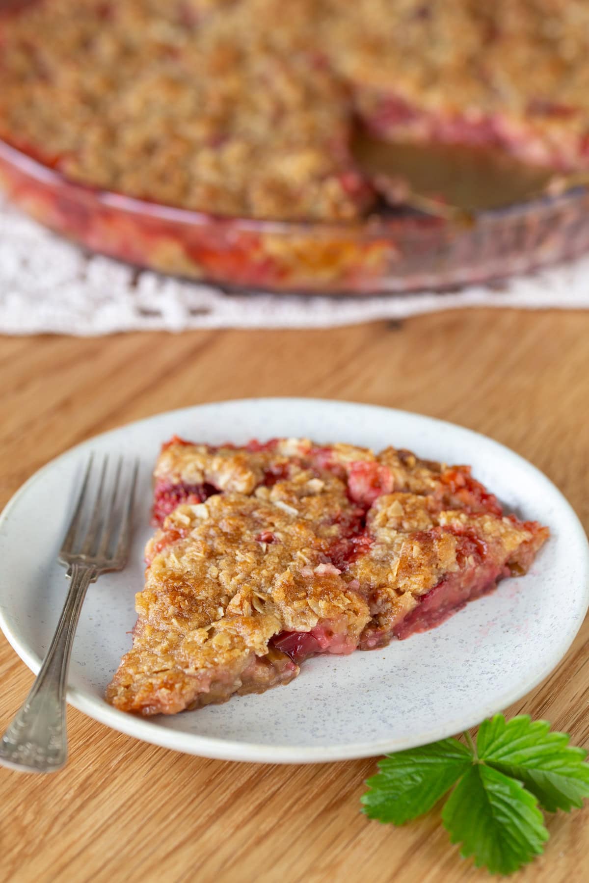 One slice of strawberry rhubarb crisp on a white plate.
