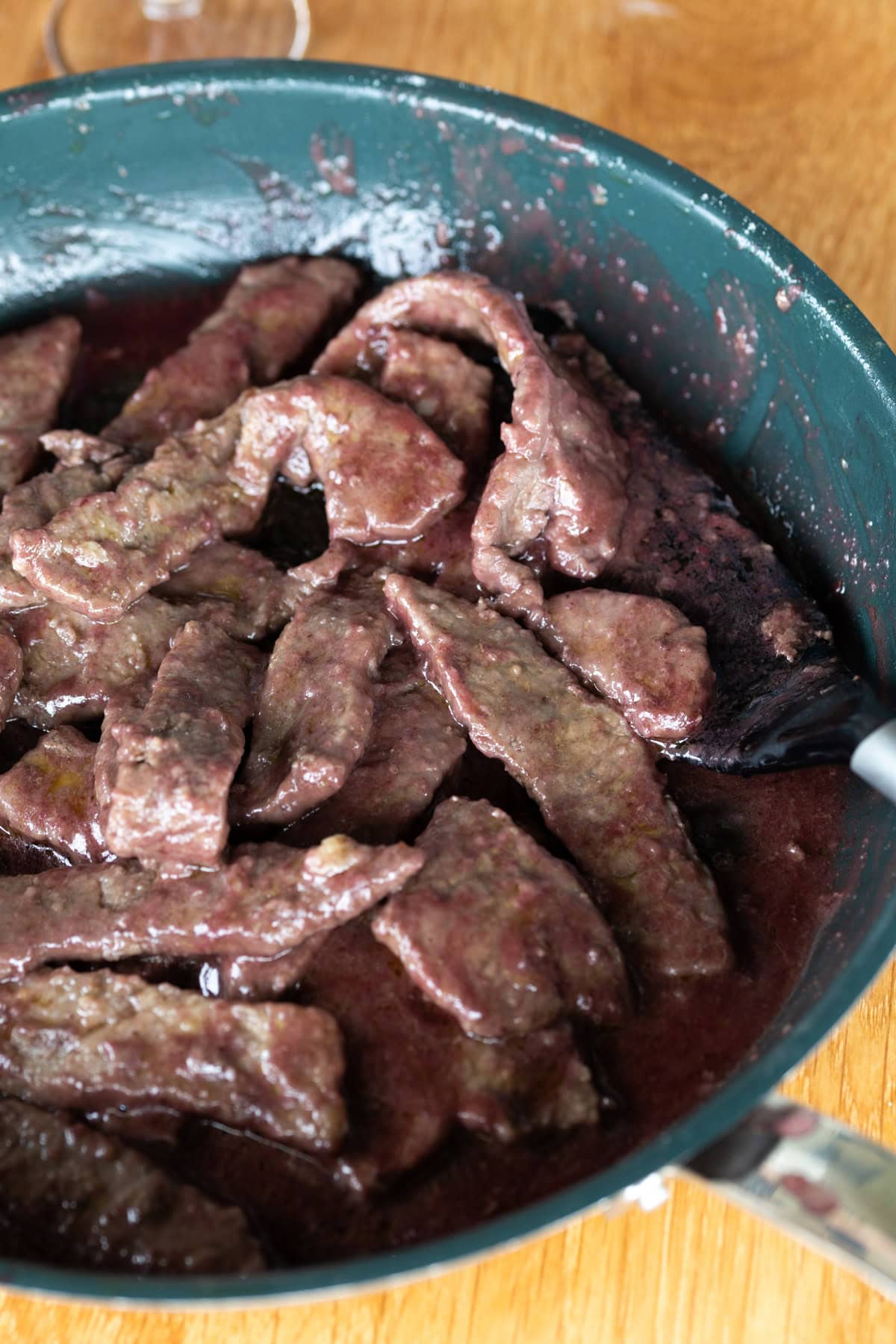 Red wine beef strips in a non stick pan.