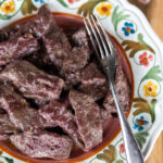 Red wine beef strips served on a very decorated plate.