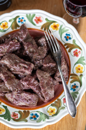 Red wine beef strips served on a very decorated plate.