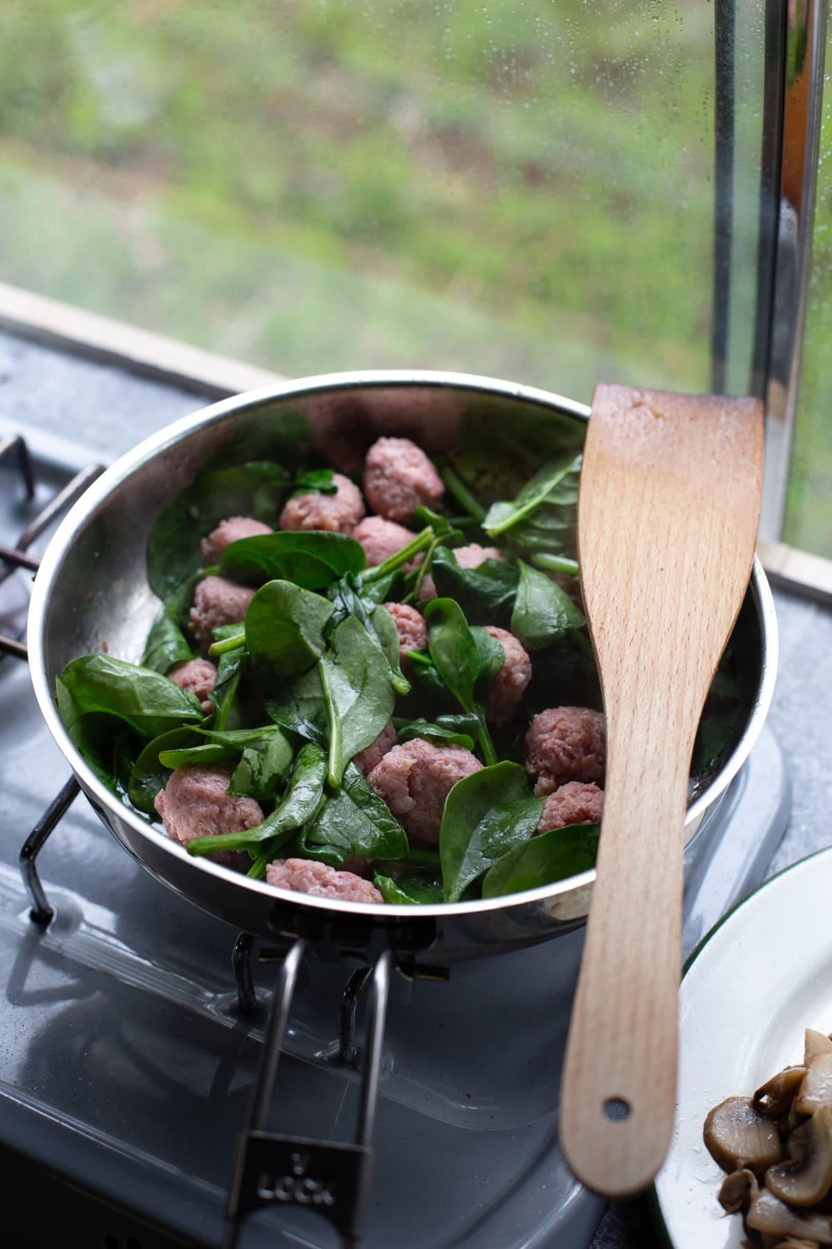 Adding spinach to salsiccia meatballs.