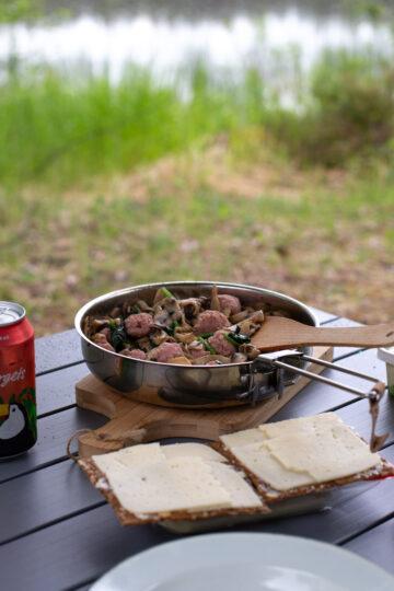 Salsiccia meatballs served with bread and cheese on a camping table.