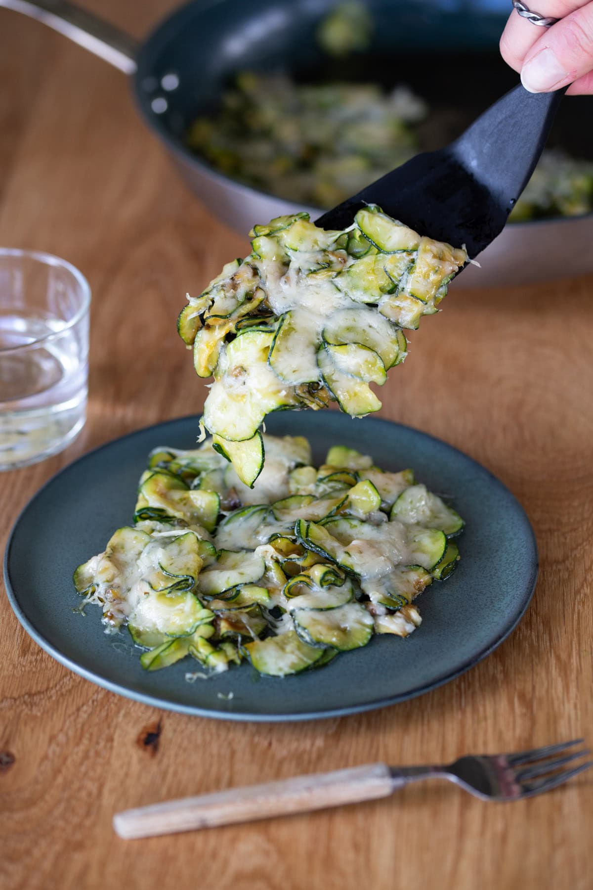 Black serving tool plating a portion of parmesan zucchini.