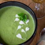 A black bowl of pea soup with mint.