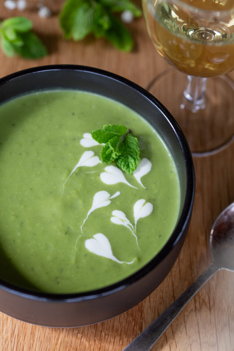 A black bowl of pea soup with mint.