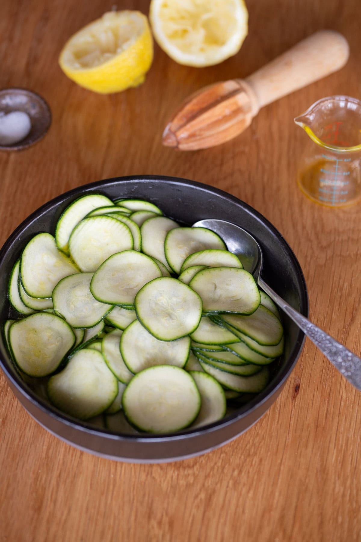 Making marinated zucchini in a black bowl.