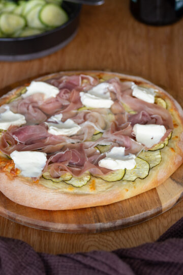 Pizza with marinated zucchini, prosciutto and cream cheese dollops.
