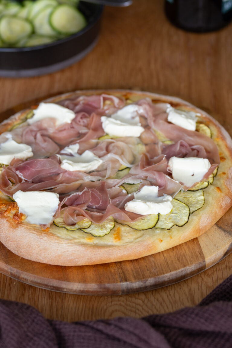 Pizza with marinated zucchini, prosciutto and cream cheese dollops.