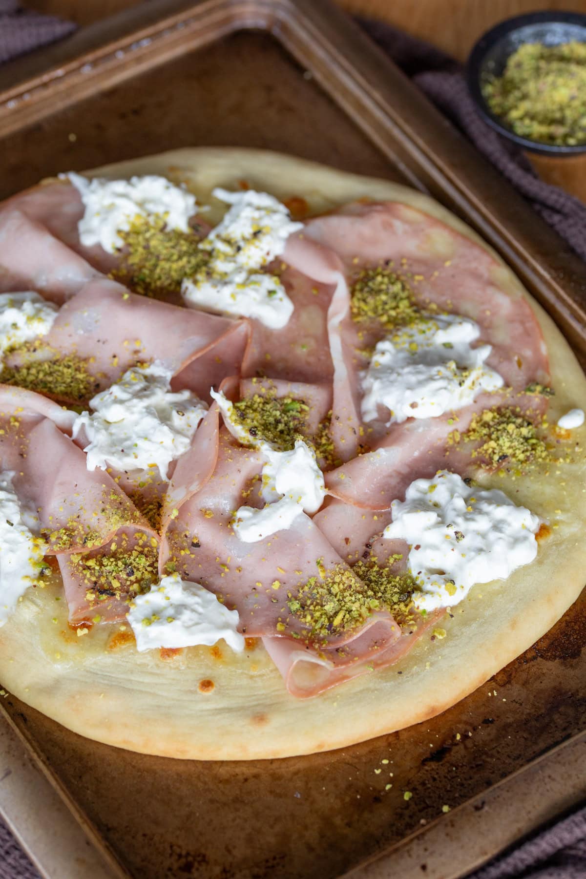 Mortadella pizza with pistachio and burrata closeup.