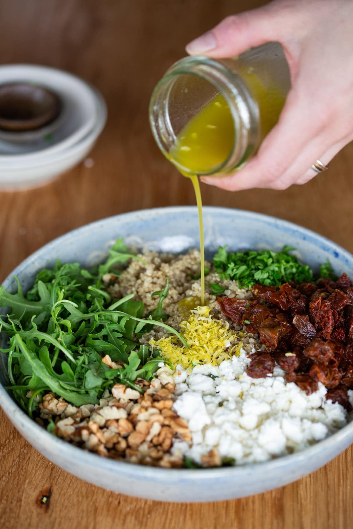 Hand pouring dressing over salad.
