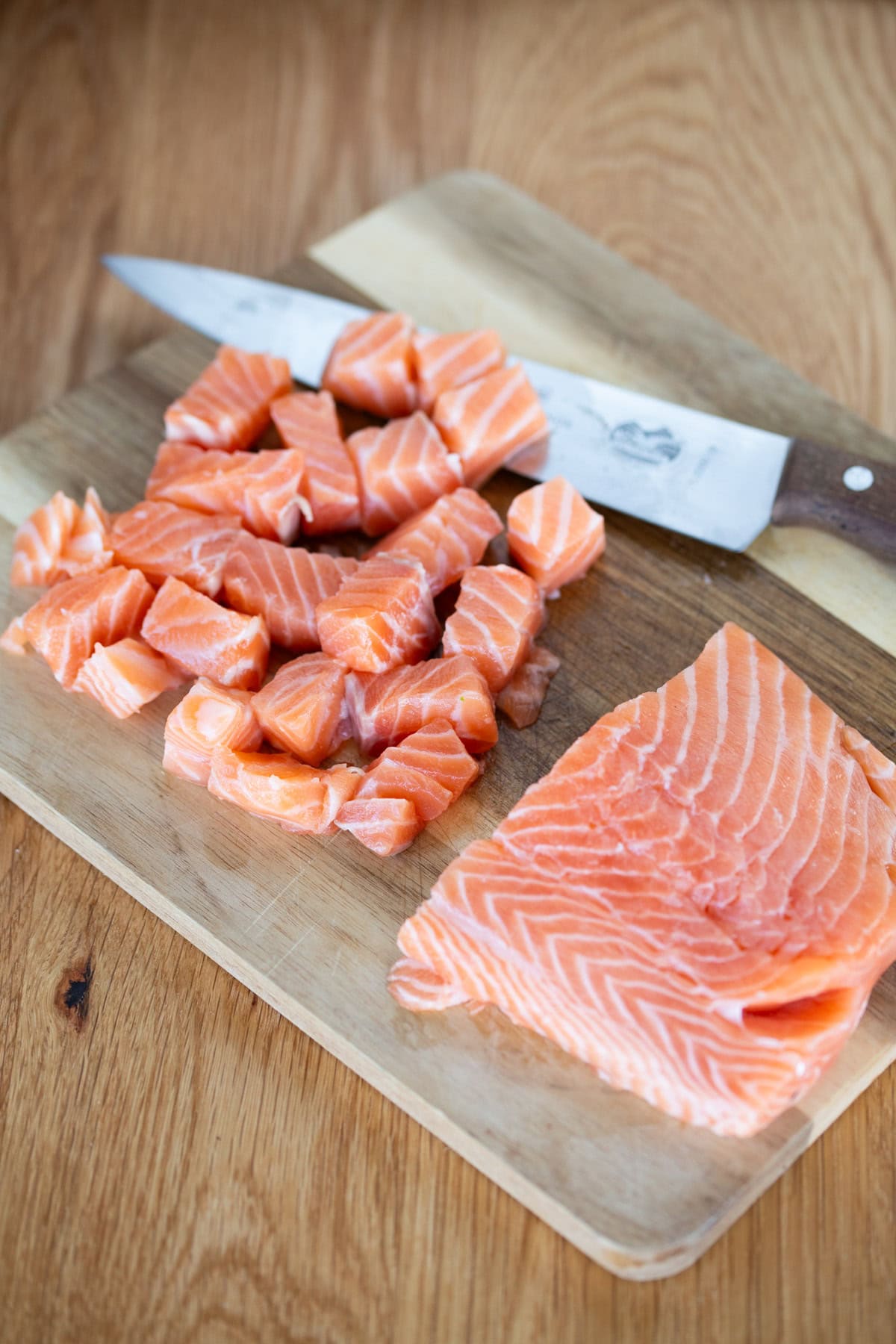 Diced salmon on a wooden board.