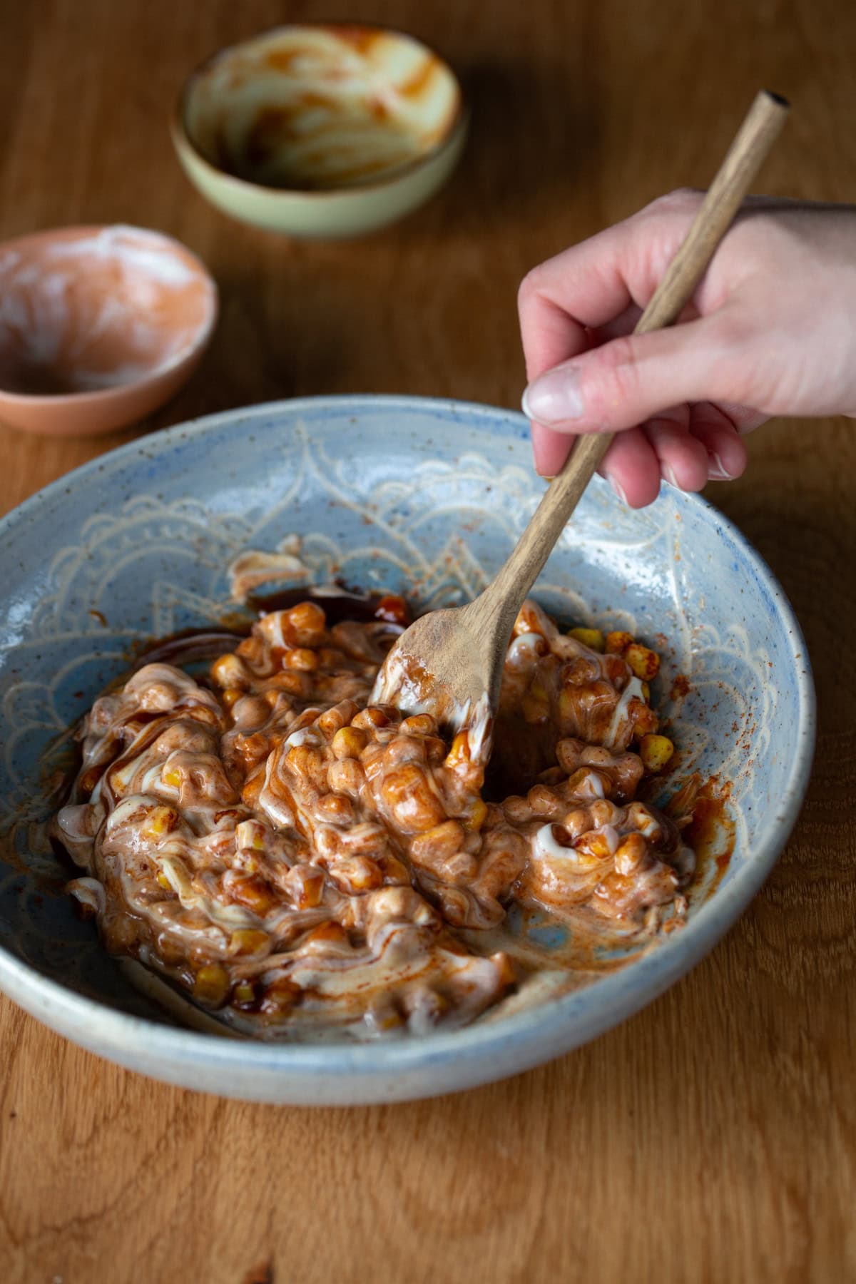 Mixing mayonnaise and barbecue sauce to corn.